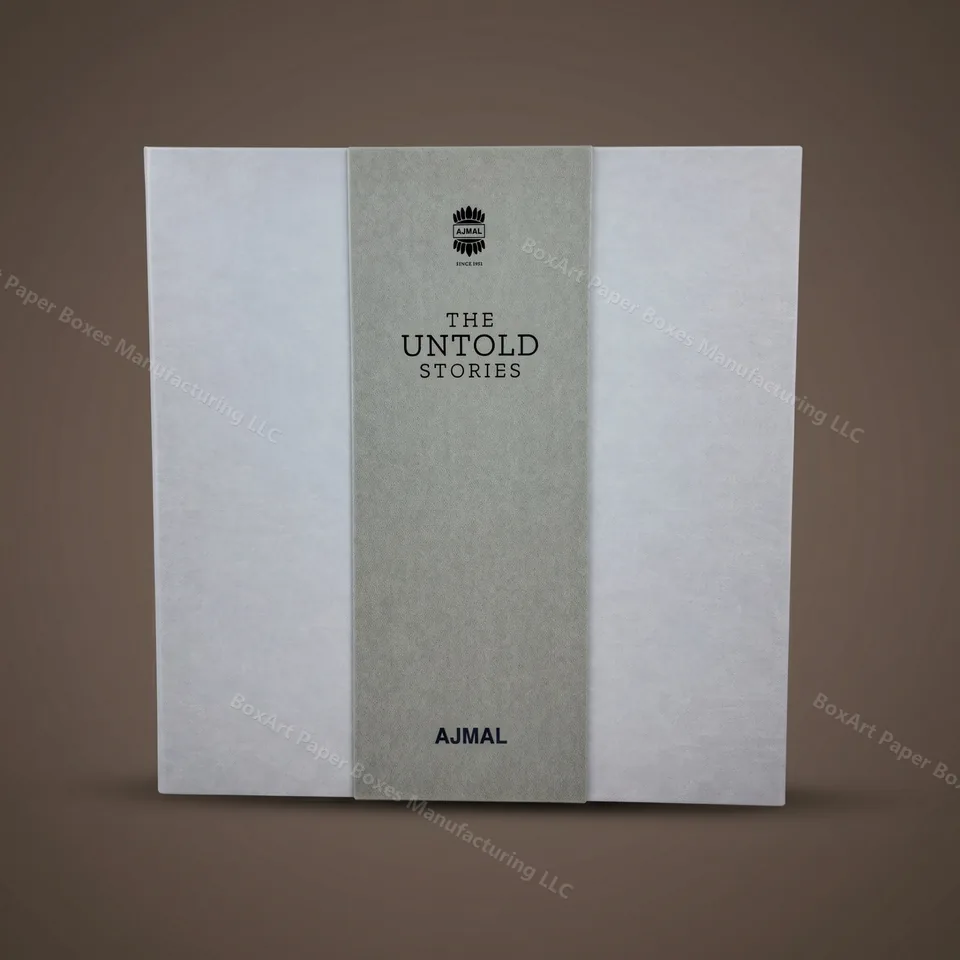 Ajmal Untold Stories — Two-Tone Suede Box — luxury perfume boxes manufactured in Dubai by BOXART — Rigid perfume book box in two-tone suede — pale ivory panels with a warm grey spine and blind-deboss AJMAL wordmark.