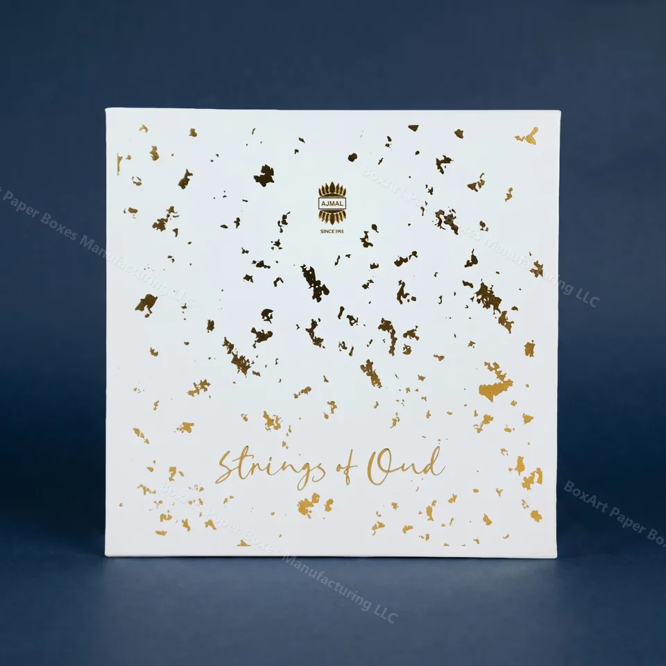 Ajmal Strings of Oud — Gold-Fleck Lid — luxury perfume boxes manufactured in Dubai by BOXART — Two-piece rigid perfume box in matt white with hand-applied gold-leaf fleck and script foil branding.