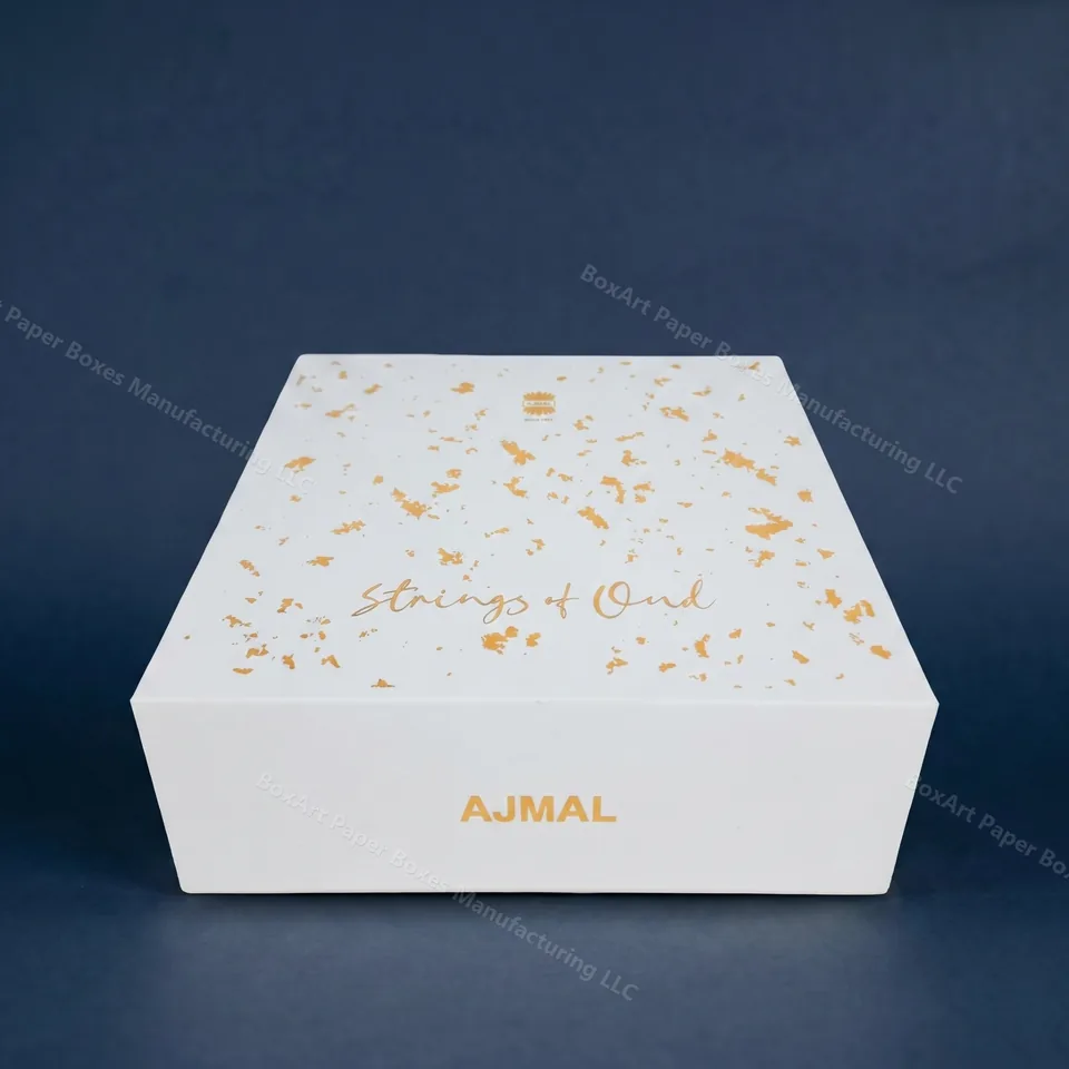 Ajmal Strings of Oud — Full Rigid Box — luxury perfume boxes manufactured in Dubai by BOXART — Full lift-off-lid rigid perfume box with matte white base, gold-leaf fleck and metallic foil AJMAL logo.